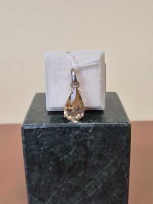 une petite boîte blanche surmontée d'un pendentif en forme de larme doré