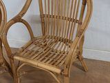 pair of rattan chairs sitting on a wooden floor in front of a white wall