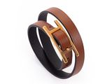 un gros plan sur un bracelet en cuir marron muni d'une boucle dorée