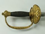 a gold sword with a black handle on a white surface