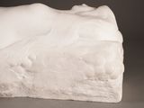 a white sculpture of a woman laying down on a rock