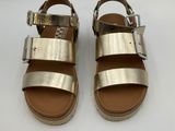 a pair of gold sandals on a white surface