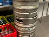 un grand fût de bière en métal posé à côté d'une caisse jaune