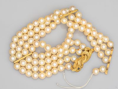 un gros plan sur un collier de perles muni d'un fermoir en or
