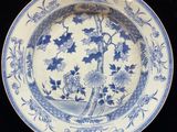 a blue and white plate with a bird and flowers on it