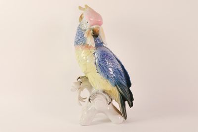 a figurine of a parrot sitting on a tree branch