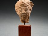 a close up of a statue of a head on a wooden stand