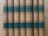 six old books are lined up on a wooden table