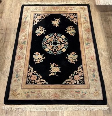 un tapis noir à motifs floraux posé sur un parquet