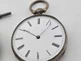 a silver pocket watch and a pair of scissors on a table