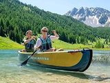 two people in a canoe on a lake with mountains in the background