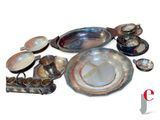 a lot of silver plates and bowls on the table