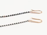 two pairs of black and white diamond earrings on a white surface