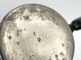 a silver pan with a handle on a white surface