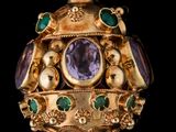 une image représentant une broche en or et en améthyste, ornée de pierres vertes et violettes
