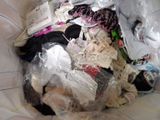 a pile of clothes in a plastic bag on a bed