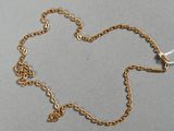 un gros plan d'un collier en or avec une chaîne posé sur une surface grise