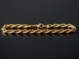 a gold bracelet with a braid design on a black background