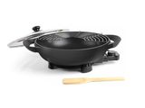 un wok noir avec une cuillère en bois sur fond blanc