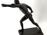 bronze statue of a man throwing a frisbee on a white background