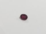 a red oval shaped ruby stone on a white surface
