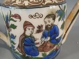 a blue and white teapot with a picture of a man and a woman on it