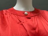 a close up of a mannequin wearing a red dress with a pearl button