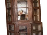 a corner cabinet with a glass door and shelves