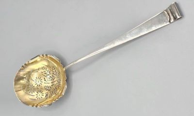 a silver spoon with a flower on it on a gray surface