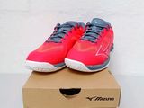 pair of red tennis shoes sitting on top of a cardboard box