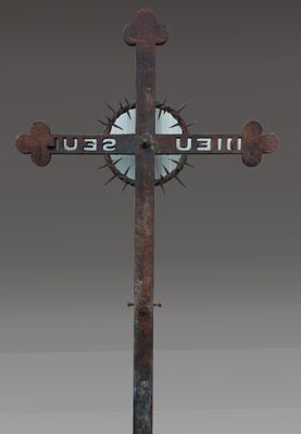 une croix en métal sur laquelle est accrochée une pancarte portant l'inscription « hell seul »