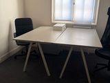 une table blanche avec une chaise noire devant une fenêtre