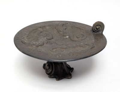 a silver plate with a snail on it on a stand