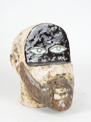 a ceramic sculpture of a man ' s face with green eyes