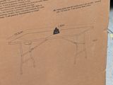 cardboard box sitting on the ground with a drawing of a table inside of it