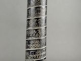 an image of a tall silver vase with designs on it