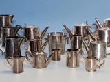 de nombreuses cafetières et tasses en argent sur la table