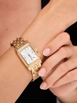 someone is wearing a gold wrist watch with a white dial