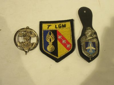 three badges are on a white surface with a black handle