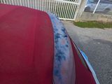 an image of a red car parked in front of a white fence