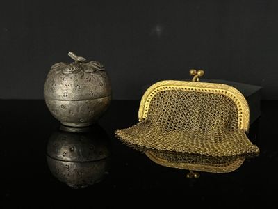 a gold purse next to an apple on a black surface