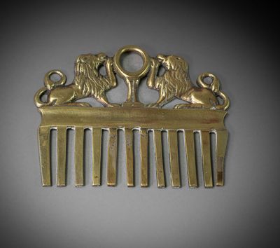 brass hair comb with two lions on it and a key in the middle of the comb