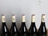 six bottles of wine are lined up on a wooden table