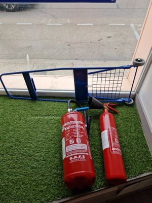two red fire extinguisors sitting on the grass outside of a window
