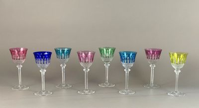 Plusieurs verres à vin de différentes couleurs sont alignés sur une table.