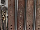 five wooden flutes are lined up on a table with a small bag