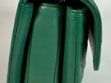 the green purse has a gold clasp on the front of it