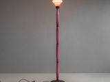un lampadaire rose avec un pied noir et une ampoule blanche