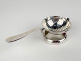 a silver strainer with a spoon in it