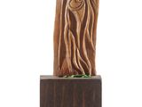sculpture of a tree trunk with a face carved into it on a wooden base